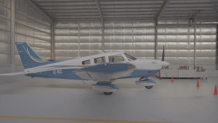 طائرة صغيرة زرقاء وبيضاء في مستودع طائرات، لقطة داخلية.