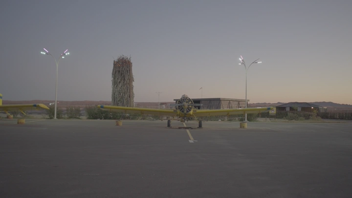 طائرة صفراء متوقفة في مطار خاص عند الغروب، منظر أمامي.