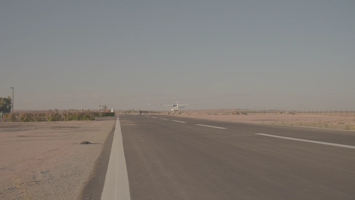 طائرة تقلع من مدرج في منطقة صحراوية، لقطة من الأرض.