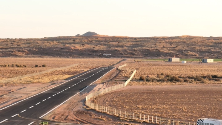 هبوط طائرة في مدرج طائرات في منطقة صحراوية، لقطة جوية.