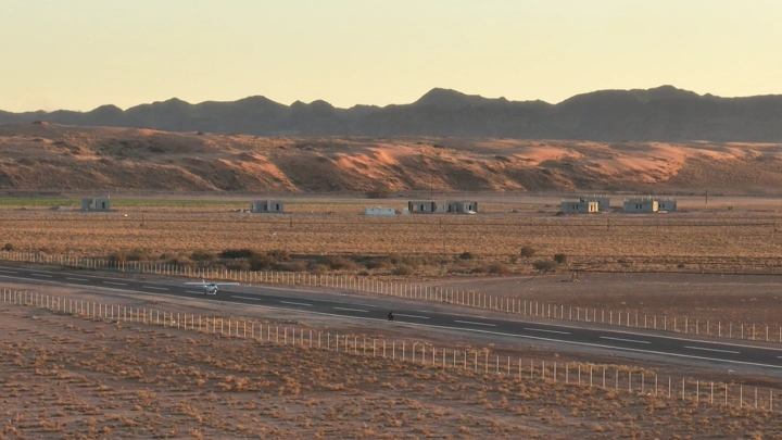 اقلاع طائرة من مدرج طائرات في صحراء عند الغروب، لقطة جوية.