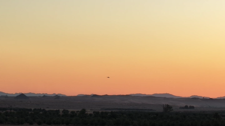 طائرة تحلق فوق صحراء عند الغروب، منظر طبيعي.