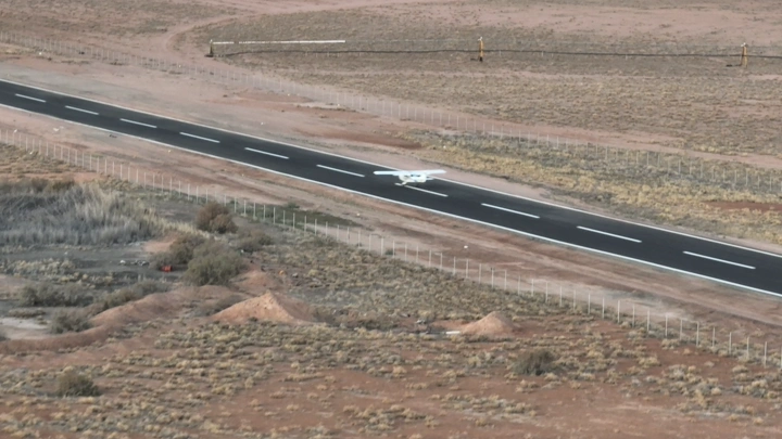 هبوط طائرة صغيرة على مدرج في منطقة صحراوية، لقطة جوية.