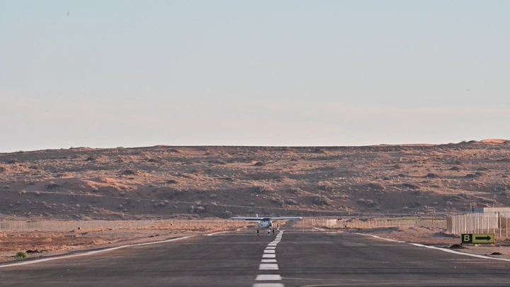 طائرة صغيرة تقلع من مدرج طائرات في منطقة صحراوية، لقطة من الأمام.