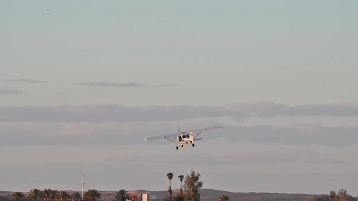 طائرة صغيرة تحلق فوق صحراء في النهار، لقطة بعيدة.