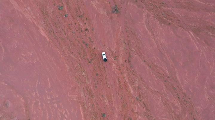 سيارة في صحراء حمراء من الأعلى، لقطة جوية.