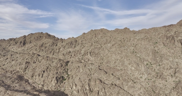 جبال صخرية تحت سماء زرقاء مع غيوم، لقطة درون.