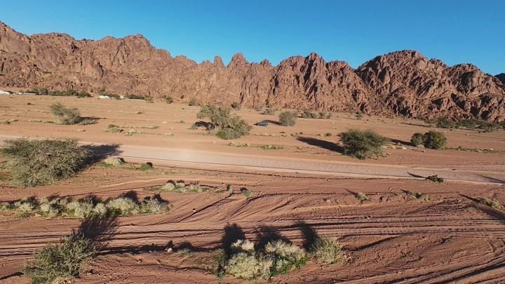 سيارة تسير في صحراء توارن حائل تحت السماء الزرقاء، لقطة درون.