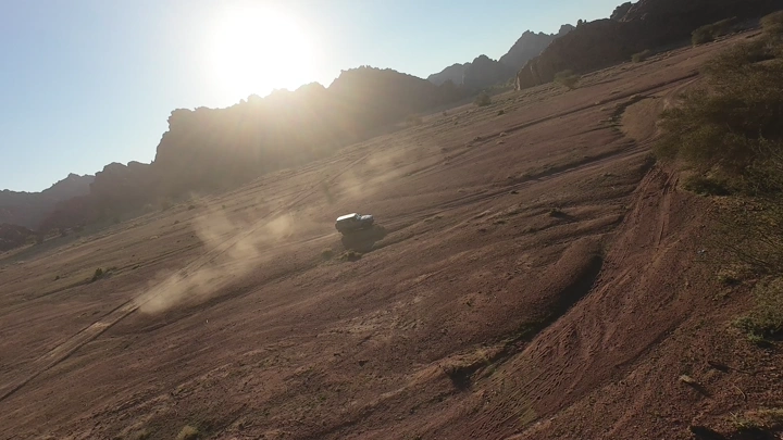 سيارة تسير في صحراء توارن حائل عند الغروب، لقطة درون.