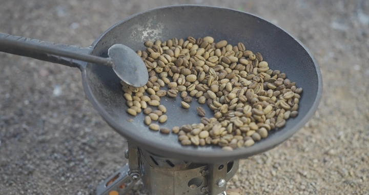 تحميص حبوب القهوة في محماسه على موقد خارجي، لقطة قريبة.