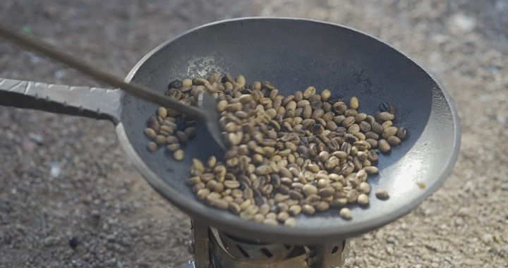تحميص حبوب القهوة في محماسه معدنية، لقطة مقربة.