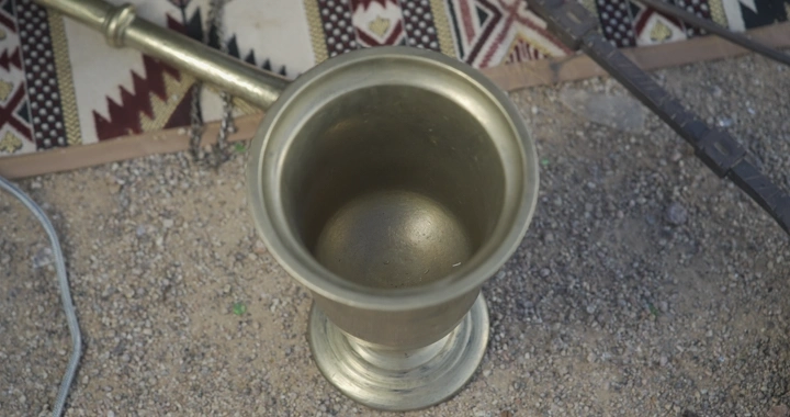 هاون معدني تقليدي على الأرضية الترابية، لقطة من الأعلى.