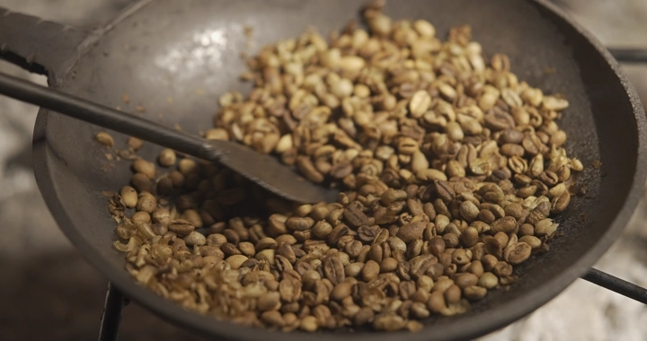 تحميص حبوب القهوة في محماسه على النار، لقطة مقربة.