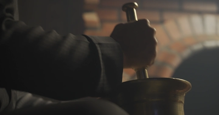 يد تطحن في النجر نحاسي، إضاءة خافتة.