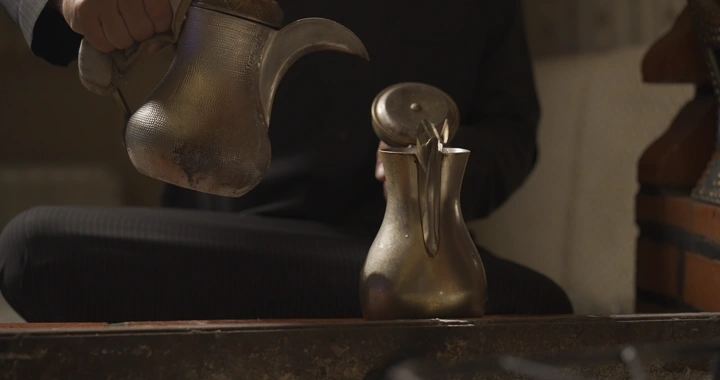 دلة قهوة سعودية تقليدية تُسكب في دلة، لقطة قريبة.