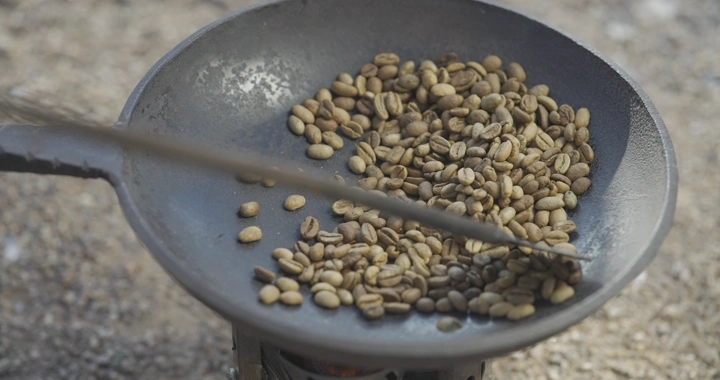 تحميص حبوب القهوة في محماسه على النار، لقطة قريبة.