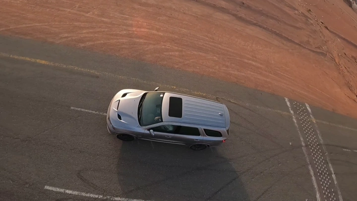 سيارة فضية على طريق صحراوي، لقطة جوية.