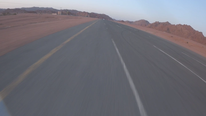 لقطة سيارة منطلقة في طريق سريع في الصحراء عند الغروب، لقطة جوية.