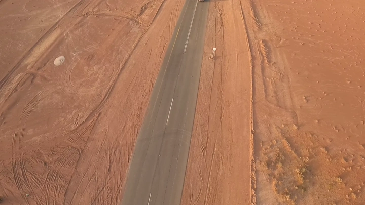 طريق صحراوي طويل مع سيارة في الأعلى، لقطة جوية.