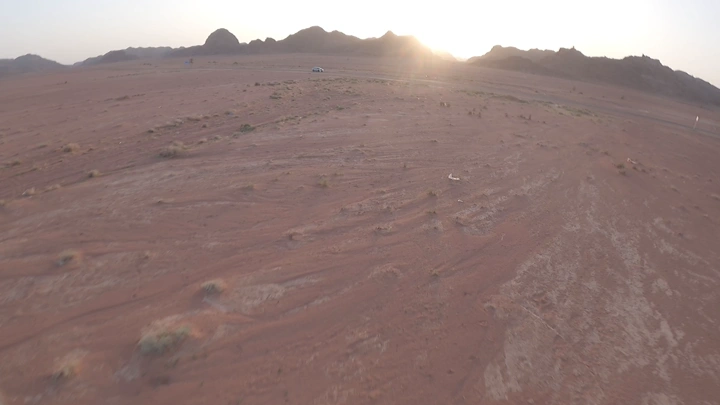 سيارة في صحراء عند الغروب، لقطة جوية.