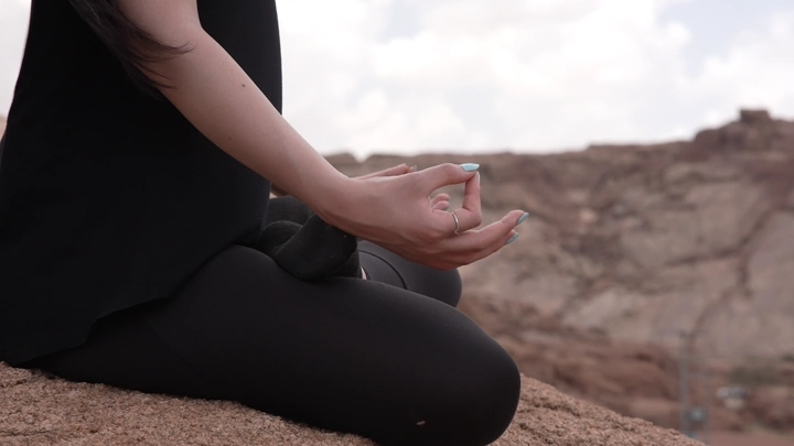 امرأة تتأمل على صخرة في الطبيعة، لقطة قريبة.