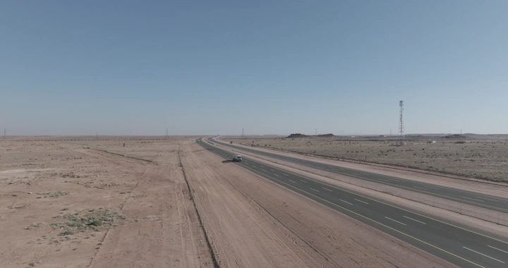 طريق سريع في منطقة صحراوية مع مرور سيارات الشحن، لقطة جوية.