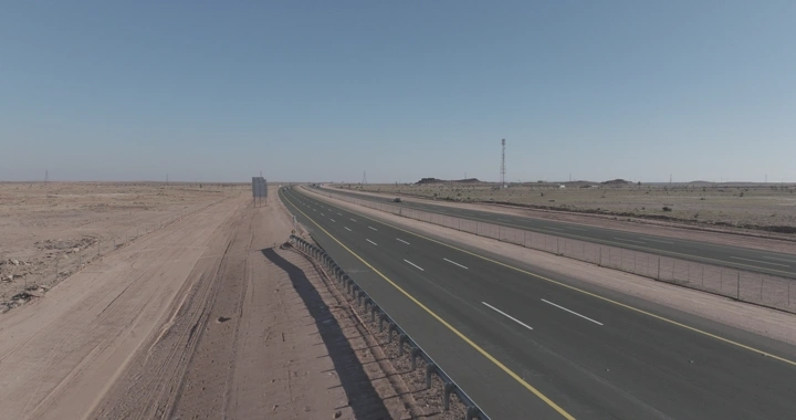 طريق سريع في منطقة صحراوية مع مرور سيارات الشحن، لقطة جوية.