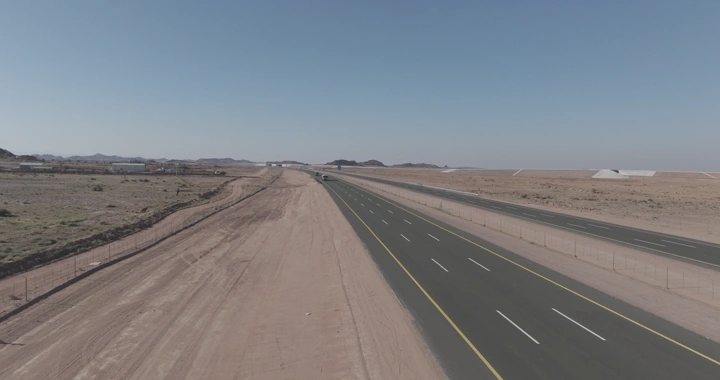 طريق سريع في منطقة صحراوية مع مرور سيارات الشحن، لقطة جوية.