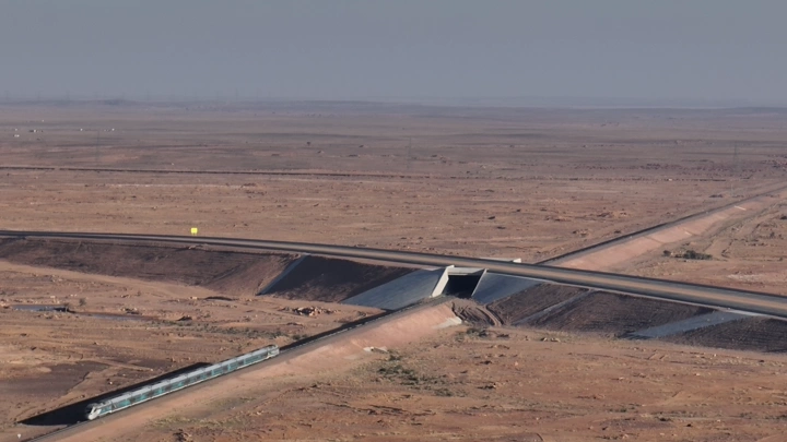 قطار يسير في صحراء شاسعة تحت سماء صافية، لقطة جوية.