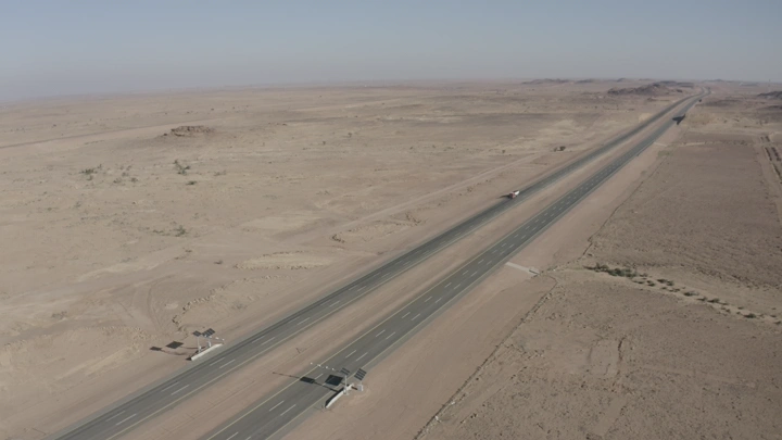 طريق سريع في منطقة صحراوية مع مرور سيارات الشحن، لقطة جوية.