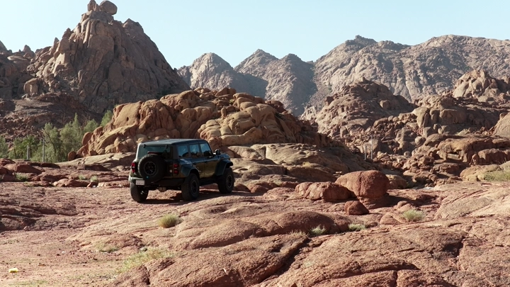 Car on rocky terrain during the day, wide shot.