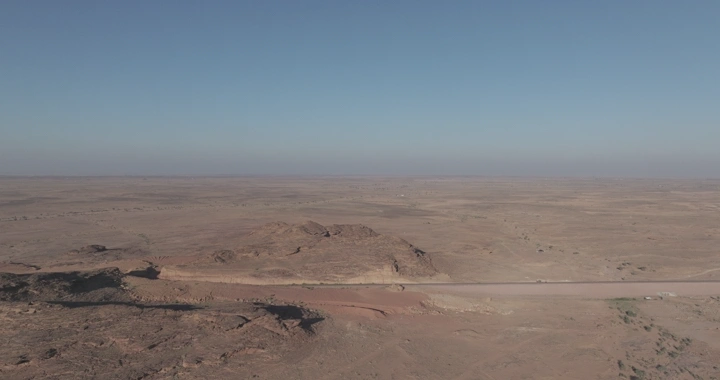 صحراء واسعة مع خط سكة حديد مع مرور القطار، لقطة جوية.