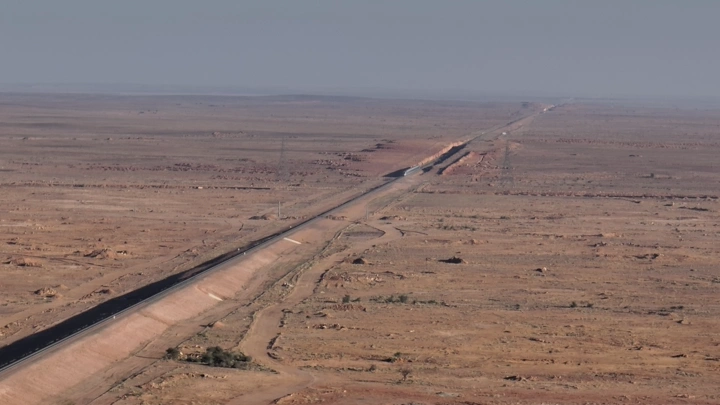 صحراء واسعة مع خط سكة حديد طويل ومرور القطار، لقطة جوية.
