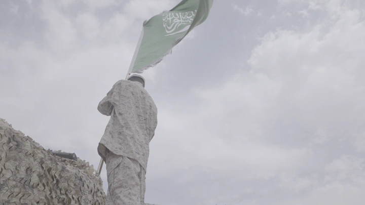 جندي يرفع علمًا في يوم غائم، لقطة من الخلف.