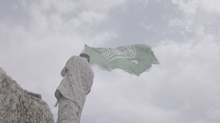 جندي يرفع علم السعودية في يوم غائم، لقطة منخفضة.