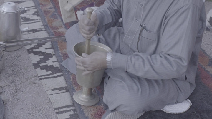 شخص يطحن القهوة في نجر على سجادة، لقطة مقربة.