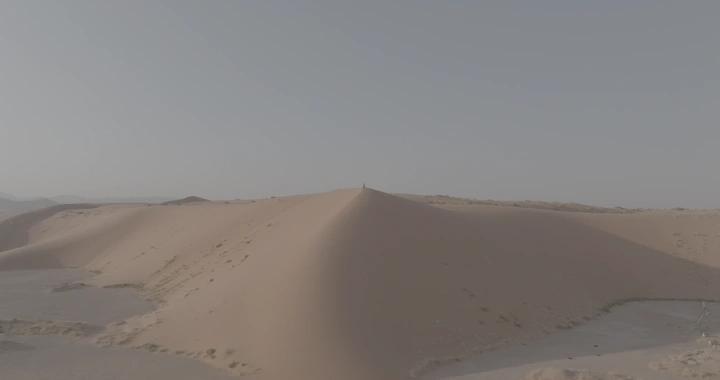 رجل يحمل علم السعودية ويقف فوق كثبان رملية في صحراء النفود، لقطة جوية.