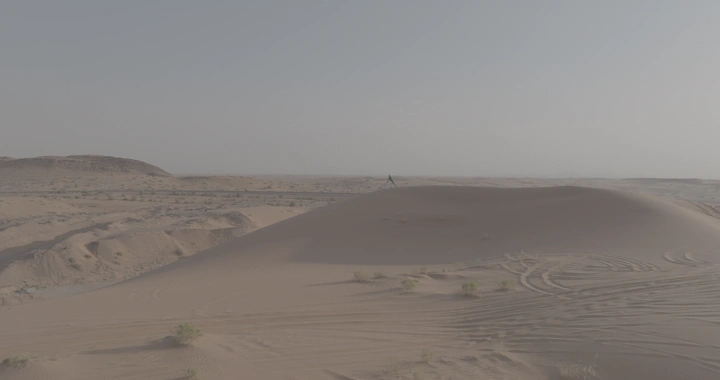 رجل يقف فوق كثبان النفود يحمل العلم السعودي، لقطة جوية.