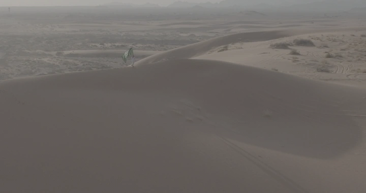 رجل يحمل علم السعودية في النفود، لقطة جوية.