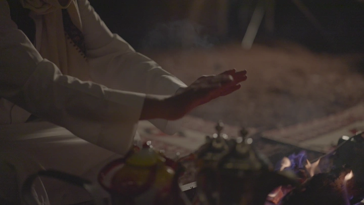 رجل يدفي يديه على النار في الليل، لقطة قريبة.