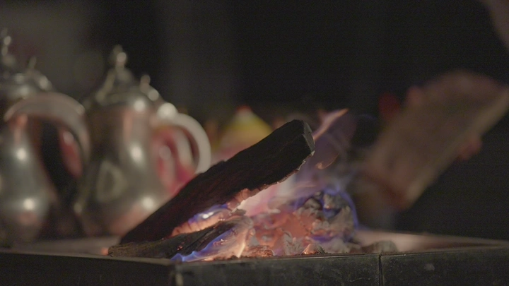 حطب مشتعل في البر مع دلال قهوة، تصوير ليلي.