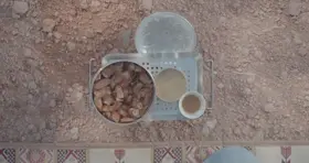 تمر وطحينة وقهوة على الأرض في الهواء الطلق، لقطة علوية.