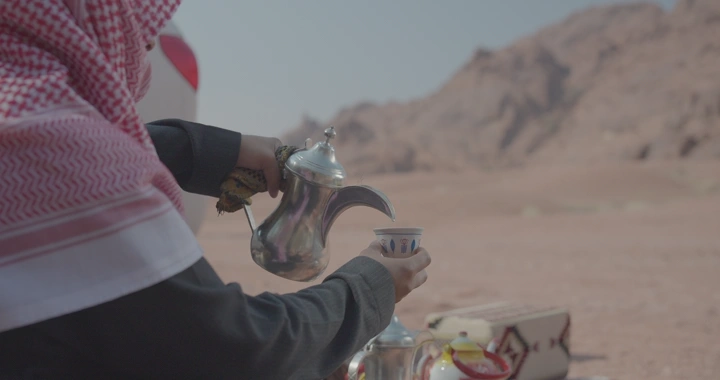 رجل يصب القهوة في الصحراء، لقطة قريبة.