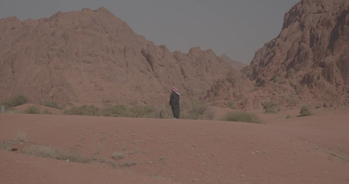 رجل يقف بين جبال حائل في النهار، لقطة بعيدة.