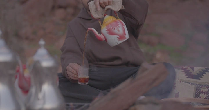 رجل يصب الشاي الأحمر في البرية، لقطة مقربة.