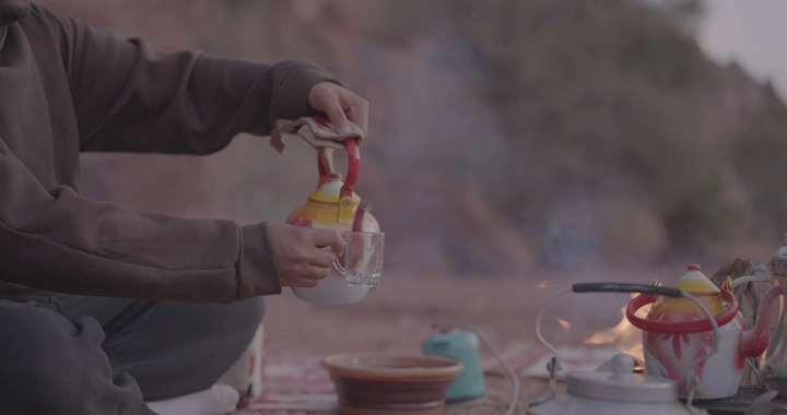 رجل يصب شاي نعناع في البرية، تصوير قريب.