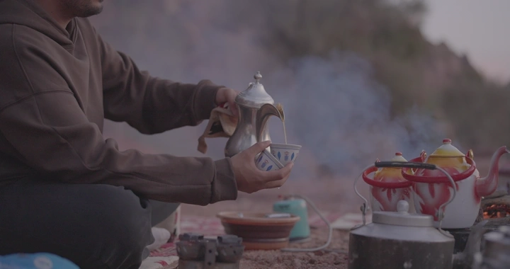 رجل يصب القهوة السعودية في البرية، صورة جانبية.