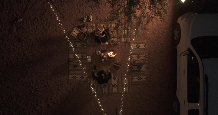 جلسة في الصحراء مع إضاءات وسيارة، لقطة من الأعلى.