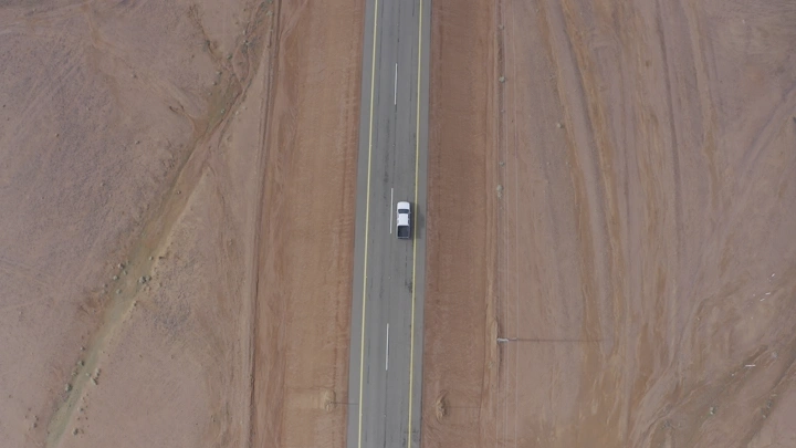 سيارة تسير على طريق صحراوي من الأعلى، لقطة جوية.