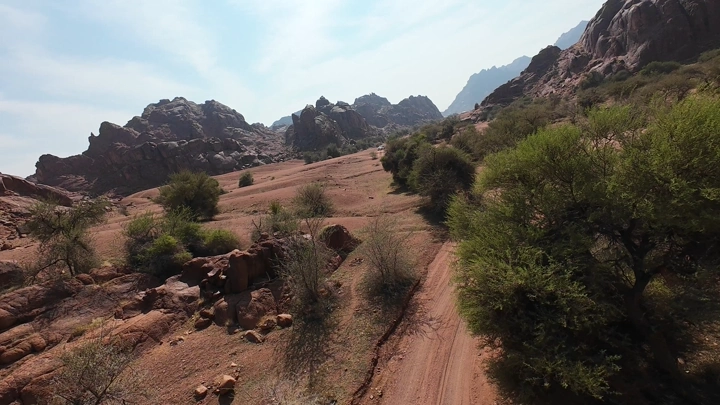 منظر جوي لجبال حائل مع طريق ترابي وأشجار متناثرة.